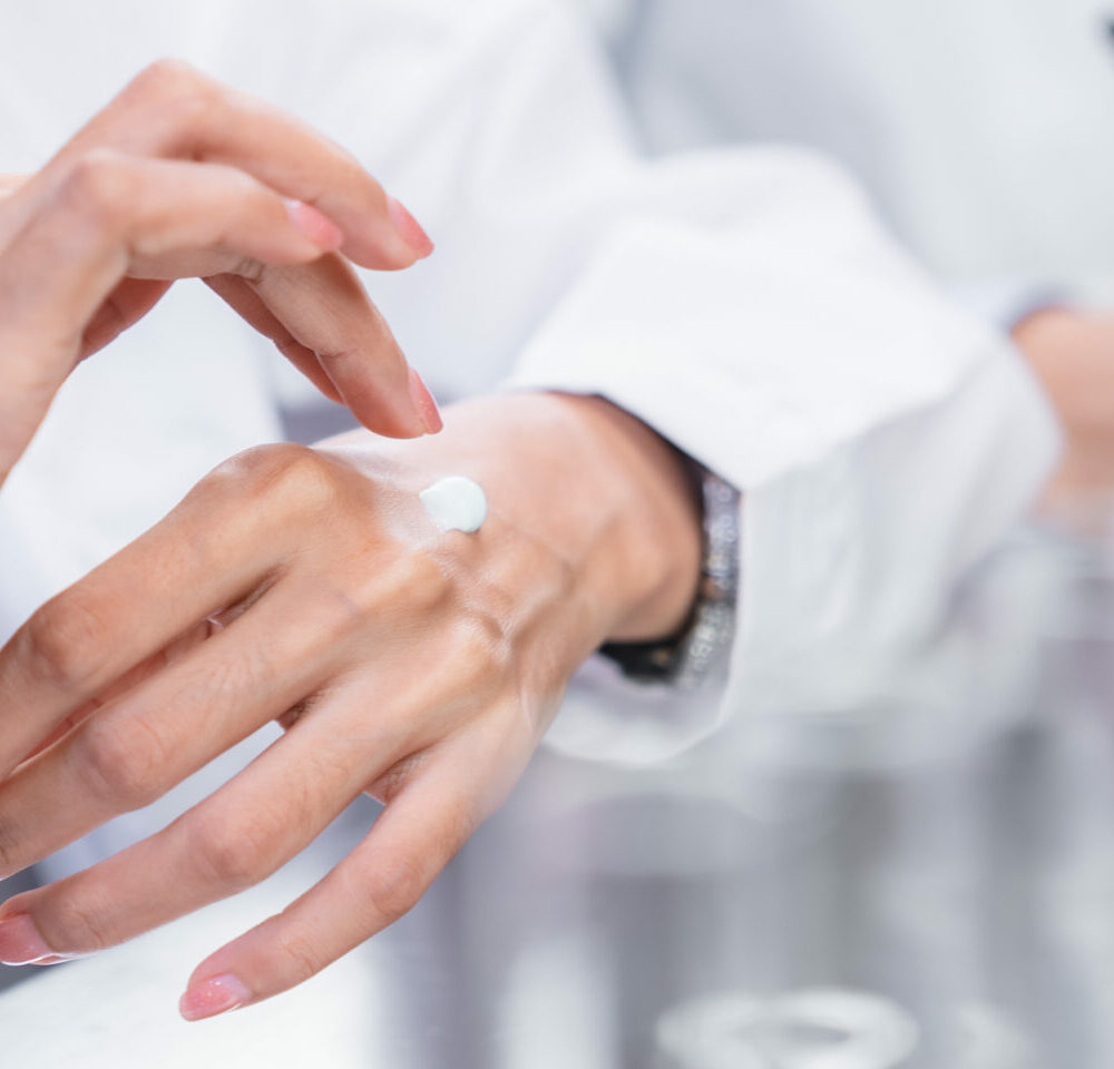 Beauty cosmetic research and development concept, Pharmacist and Scientist applying moisturizer lotion on her hand for efficacy testing of natural organic skincare products in biological laboratory
